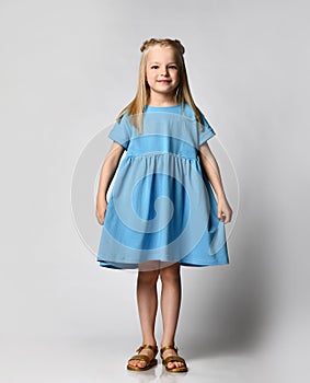 Studio portrait of a cute beautiful little girl in a blue summer dress on a white background.