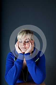Studio portrait of a cute blond girl bored with heads in hands