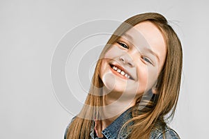 Studio portrait of a cute little girl on a gray background. kid smiling
