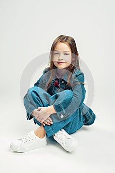 Studio portrait of a cute little girl. kids fashion child in denim pants and jacket and white sneakers