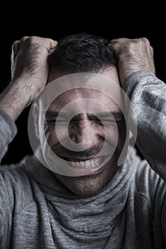 Portrait of a desperate man with hands on his head. Black background. Vertical