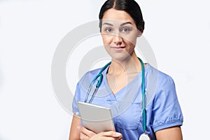 Studio Portrait Of Female Nurse Wearing Scrubs Holding Digital Tablet