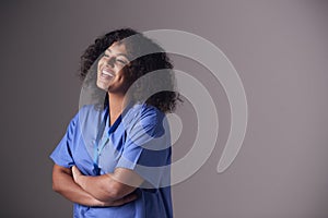 Studio Portrait Of Female Nurse Wearing Scrubs Standing Against Grey Background