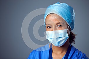 Studio Portrait Of Female Surgeon Wearing Scrubs And Face Mask