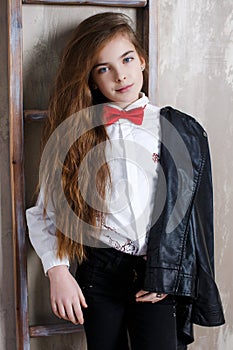 Studio portrait of a girl in a white shirt with a bow tie on a gray background