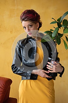 Studio portrait of glamorous lady in punk rock style party clothes with dark pink mohawk in casual dress, black leather