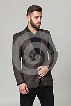 Studio portrait of handsome elegant young man in brown jacket po