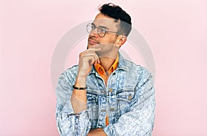 Studio portrait of a handsome thoughtful young man  thinking an idea posing over isolated pink background. Male wearing stylish