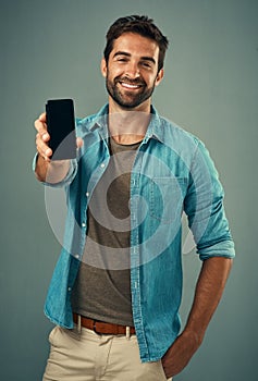 Take a look and tell me what you think. Studio portrait of a handsome young man holding a cellphone with a blank screen