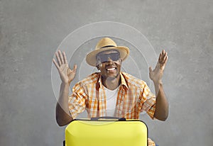Studio portrait of a happy cheerful black tourist with his yellow travel suitcase