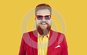 Studio portrait of happy funny bearded fat guy in red suit, yellow shirt and cool sunglasses