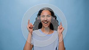 Studio portrait happy smiling singing Arabian woman Indian lady Hispanic girl listening to music with headphones dancing