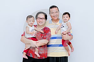 Studio portrait of happy young family with little children. Parents At Home Cuddling Twin Baby Daughters In Nursery .