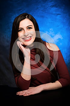 In studio portrait of high school senior girl in red shoulder top and blue background