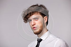 Studio portrait of incredulous young man being offended and upset, standing over gray background, expressing sadness and negative