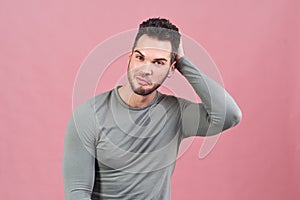 Studio portrait on an isolated background of a young athletic man smiling and scratching his head pondering over the proposal