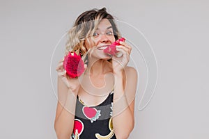 Studio portrait of joyful lady with tanned skin posing with tasty pitahaya. Indoor photo of beautif