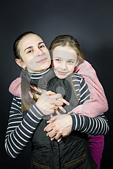 Studio portrait of a loving mother and daughter, tenderly and strongly hugging and holding hands