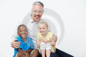 Studio Portrait Of Male Pre School Teacher With Pupils