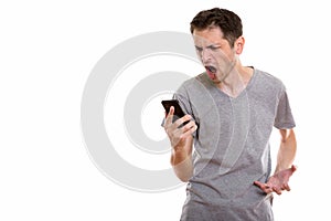 Studio shot of angry young man shouting while using mobile phone