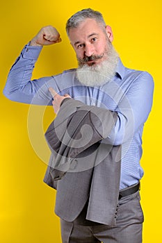 Studio portrait mature businessman dressed in grey suit shows his pumped up biceps, strong business, exercising in