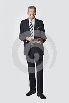 Studio Portrait Of Mature Businessman Holding Digital Tablet