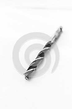 An studio portrait of a metal high speed steel wood drill bit lying down with a white background. The tool is used by a carpenter