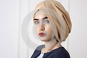 Studio portrait of oriental girl with a beautiful face with headdress turban on the classic light background