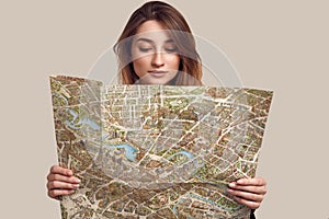 Studio portrait of pretty young hipster woman with backpack holding map