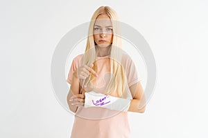 Studio portrait of sad injured young woman with broken arm wrapped in plaster bandage with funny inscription looking at