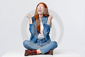 Studio portrait satisfied, happy and relieved redhead female, teen girl celebrating winning prize, triumphing sitting on