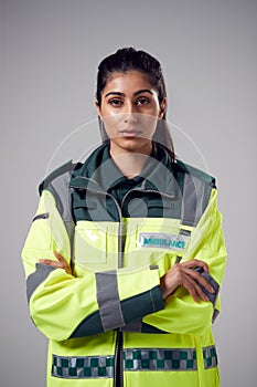 Studio Portrait Of Serious Young Female Paramedic Against Plain Background