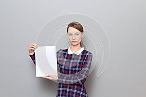 Studio portrait of serious young woman holding white blank paper sheet