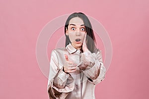 Studio portrait of a shocked funny brunette girl widely opened her eyes and mouth in surprise.