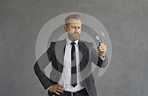 Studio portrait shot of concentrated businessman in suit with magnifier