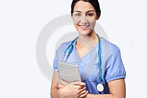 Studio Portrait Shot Of Female Nurse Wearing Scrubs Using Digital Tablet