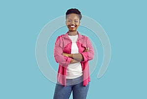 Studio portrait of smiling and confident African American woman on light blue background.