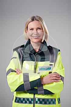 Studio Portrait Of Smiling Mature Female Paramedic Against Plain Background