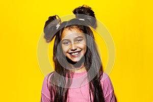 Studio portrait of smiling teenage girl on background of yellow color.