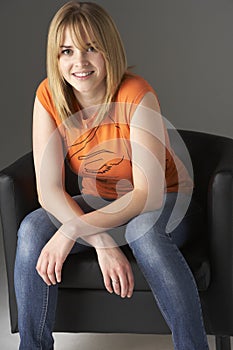 Studio Portrait Of Teenage Girl Sitting In Chair