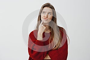 Studio portrait of thinking attractive european woman, feeling confused and troubled, looking up with concerned