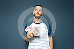 Studio portrait of thoughtful man, holding money, bunch of banknotes, Moldovan leu.