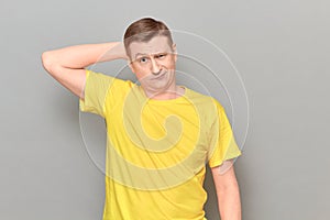 Studio portrait of thoughtful perplexed man holding hand behind head