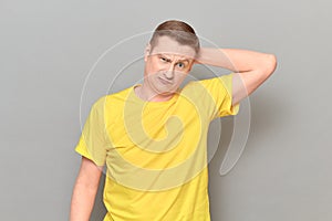 Studio portrait of thoughtful perplexed man holding hand behind head