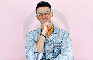 Studio portrait of a thoughtful young man thinking an idea posing over isolated pink background. Male wearing stylish casual