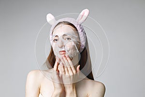 Studio portrait of a woman apply tissue mask on her face