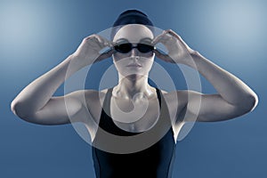 Studio portrait of woman swimmer with swimming goggles swimcap swimsuit