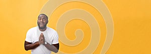 Studio portrait of young African American man in white shirt, holding hands in prayer, looking at the camera with