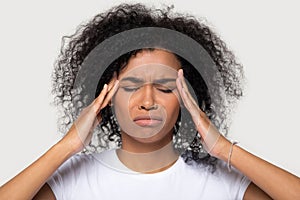 Studio portrait young african female touch temples suffers from headache