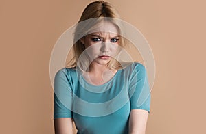 Studio portrait of young angry woman with blue eyes. Sad girl face. Youth and skin care concept.